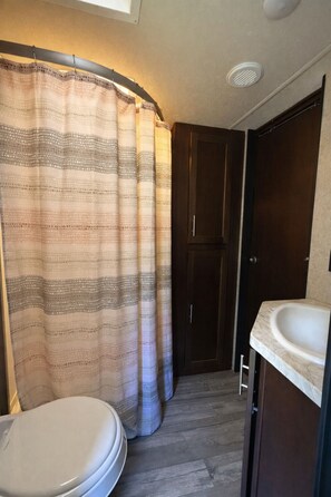 A compact bathroom with a shower curtain, a toilet, and a sink.