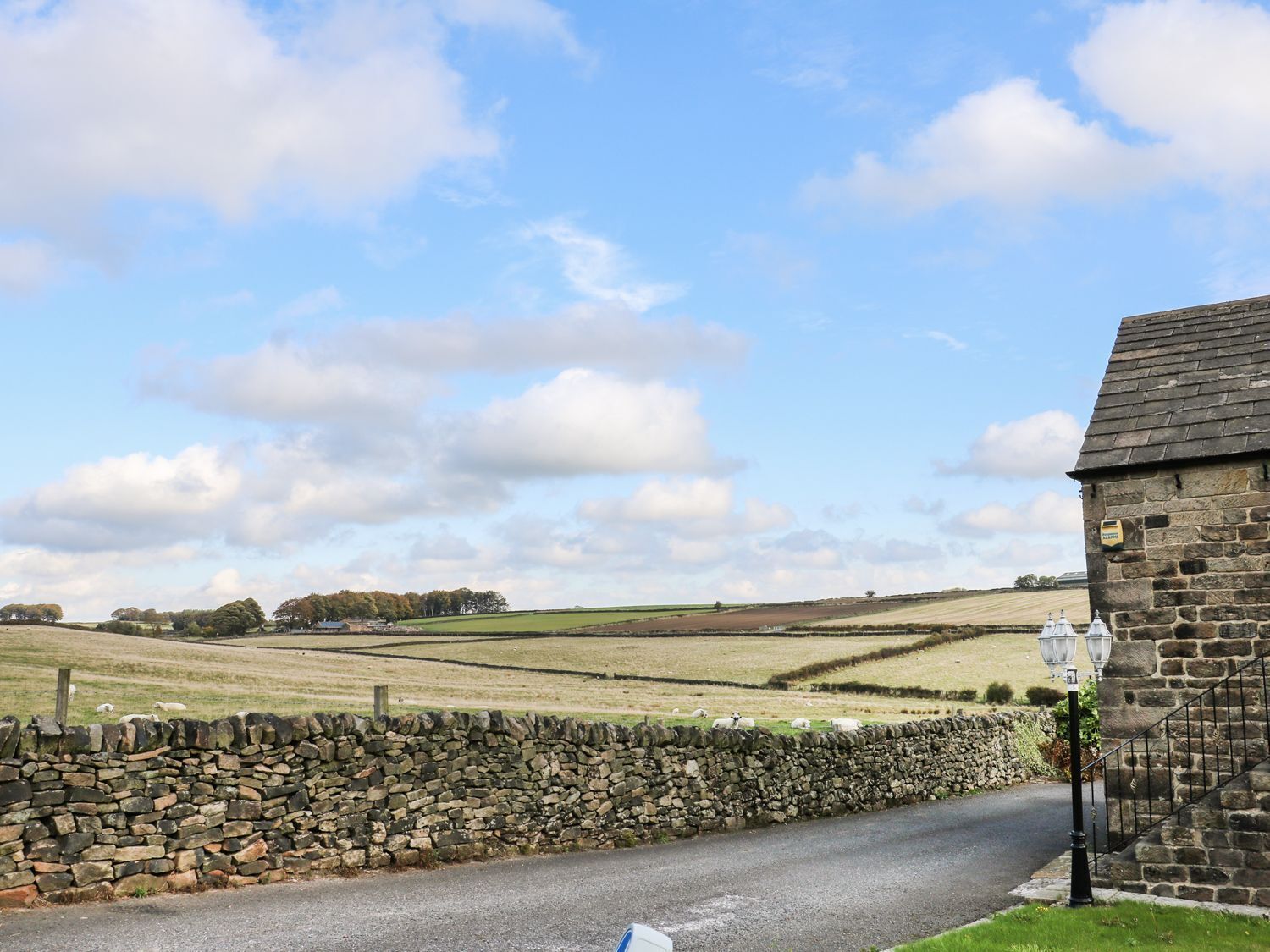 A rural road with stone walls and a stone building with a sign.