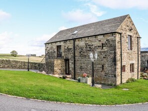 A stone building with a pitched roof, a small porch, and a stone wall in the background. - Riber View Barn (Chesterfield)