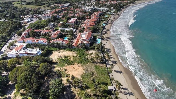 An aerial view of a coastal resort with beachfront properties, a sandy beach, and a clear view of the ocean. - Cabarete Center 2 BR Condo with a Cozy Terrace (Cabarete)