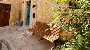 A stone building with a wooden bench and a blue door. - Kappella Boutique - Room 4 (Zurrieq)