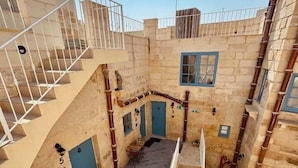 A multi-level courtyard with stone walls, multiple staircases, and blue doors. - Kappella Boutique - Room 4 (Zurrieq)