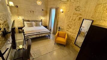 A bedroom with a bed, a chair, a desk, and a mirror.