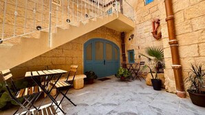 Un cortile con una porta blu, posti a sedere all'aperto e piante in vaso.