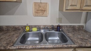 A kitchen with a granite countertop, a double sink, and wooden cabinets.