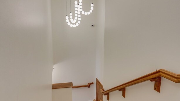 A staircase with wooden steps and a handrail, leading to a landing with a modern light fixture.