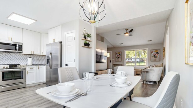 A modern kitchen with white cabinetry, stainless steel appliances, and a dining area with a white table and chairs. - Georgetown Getaway, Sleeps 6, Fenced Yard (Pet-Friendly), Near Lexington & I-75 (Georgetown)