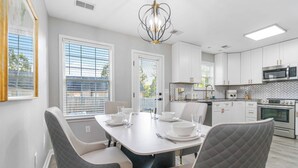 A modern kitchen with white cabinets, a built-in microwave, and an oven. There is a dining table with chairs and a chandelier above. - Georgetown Getaway, Sleeps 6, Fenced Yard (Pet-Friendly), Near Lexington & I-75 (Georgetown)