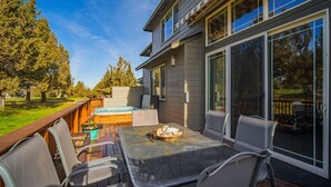 Une terrasse dotée de mobilier d’extérieur, d’un jacuzzi et d’une grande porte-fenêtre coulissante donnant sur un espace patio abrité.