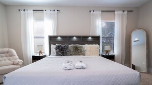 A neatly made bed with a quilted cover, two rolled towels, and three fluffy pillows. - 3-Bedroom Luxury House (Orlando)