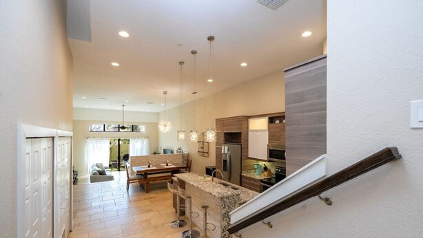 A modern kitchen with granite countertops, stainless steel appliances, and pendant lighting. - 3-Bedroom Luxury House (Orlando)