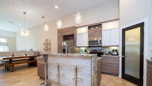 A modern kitchen with a central island, stainless steel appliances, and pendant lighting. - 3-Bedroom Luxury House (Orlando)