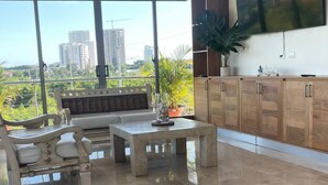 Un salón espacioso con una televisión grande, armarios de madera, un sofá y una mesa de comedor.