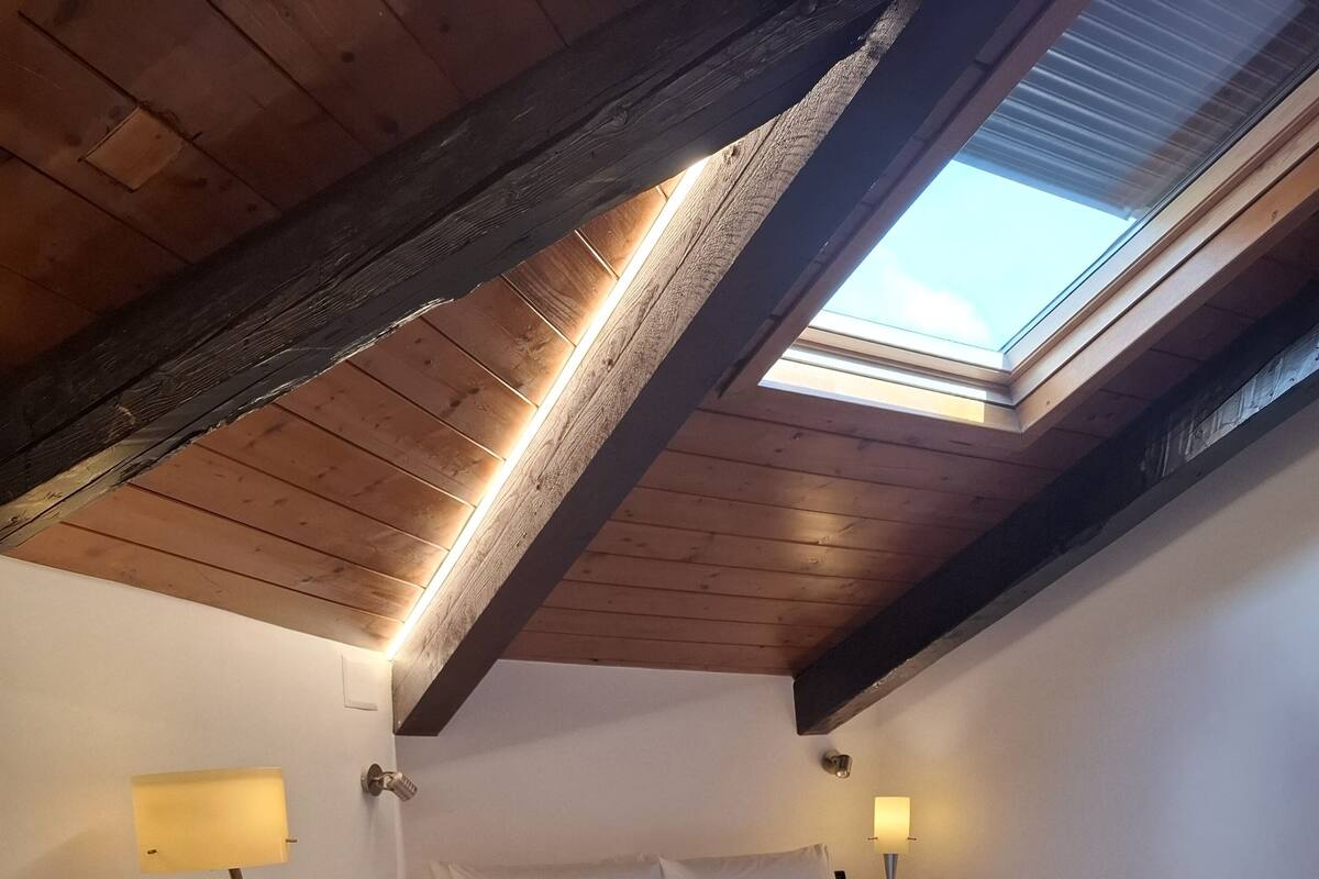 Une chambre à coucher avec un puits de lumière, un lit, une commode en bois et des lampes de chevet.