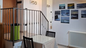Uma sala de jantar com mesa, cadeiras, escada e obras de arte nas paredes.