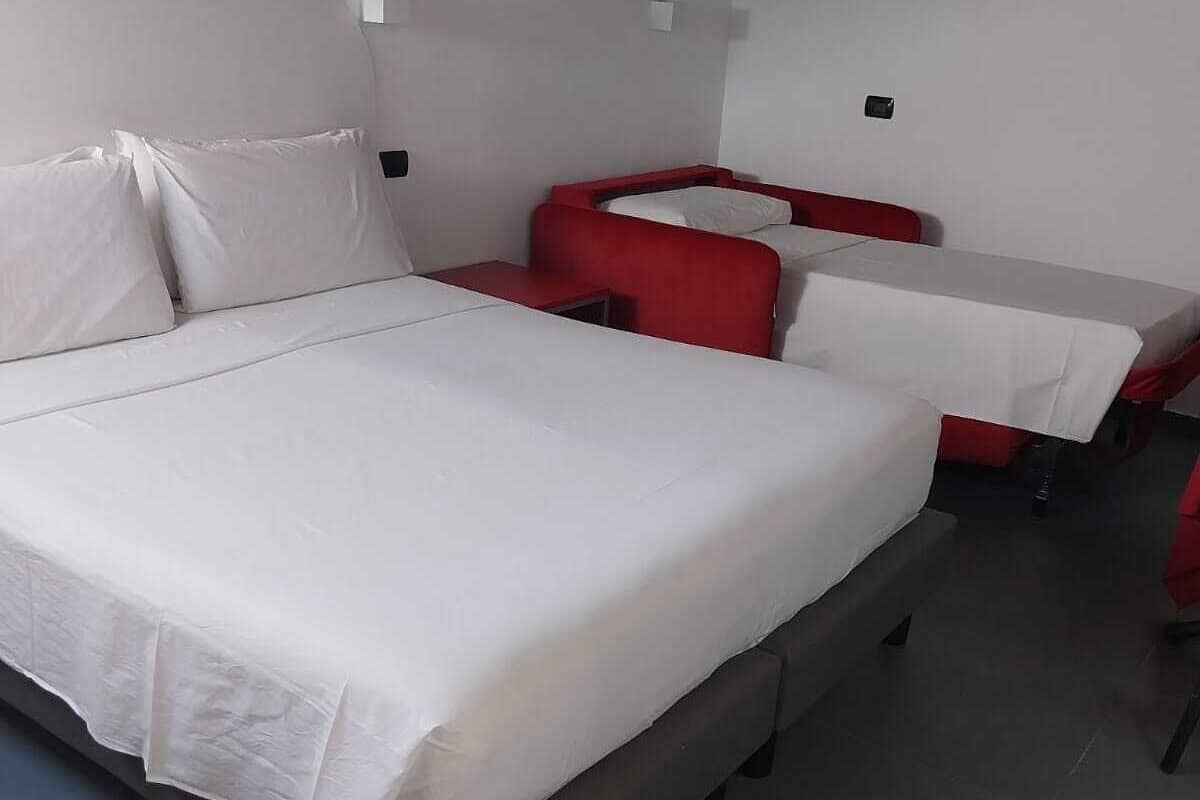 Une chambre à coucher avec un lit, une petite table et une chaise rouge.