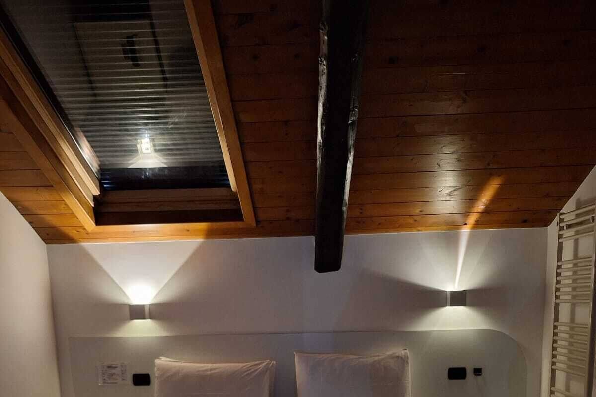 Une chambre avec un grand lit, deux tables de chevet et une lucarne.