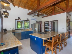 A spacious kitchen with a large island, blue cabinets, and a wooden ceiling. - Peaceful Private Natural Paradise. Private pool. Restaurant & Bar, Dive Shop (Roatan)