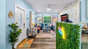 A modern living room with a blue wall, a wooden floor, a blue sofa, a coffee table, and a decorative mirror.