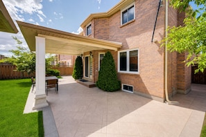 A residential building with a covered patio, brick exterior, and a well-maintained lawn. - Lower-level house in peaceful Richmond Hill with AC and charm (Richmond Hill)