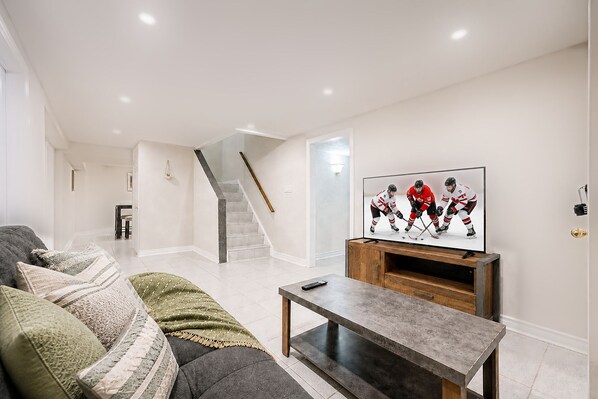 A living room with a sofa, a coffee table, and a television on a wooden stand.