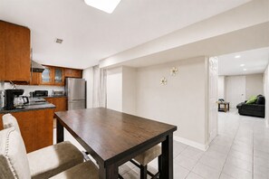 A modern kitchen with wooden cabinets, stainless steel appliances, and a dining table with chairs. - Lower-level house in peaceful Richmond Hill with AC and charm (Richmond Hill)