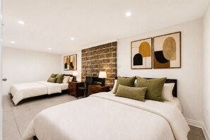 A hotel room with two beds, a stone accent wall, and artwork on the walls.