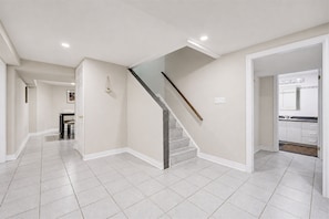 A spacious hallway with a staircase leading to a kitchen area. - Lower-level house in peaceful Richmond Hill with AC and charm (Richmond Hill)