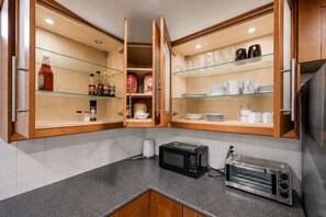 A kitchen with open cabinets displaying condiments, a toaster, and a coffee maker. - Entire comfy lower-level classic in Richmond Hill (Richmond Hill)