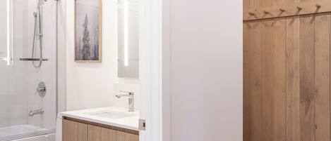 Un baño moderno con cabina de ducha de vidrio, lavamanos blanco y muebles de madera.