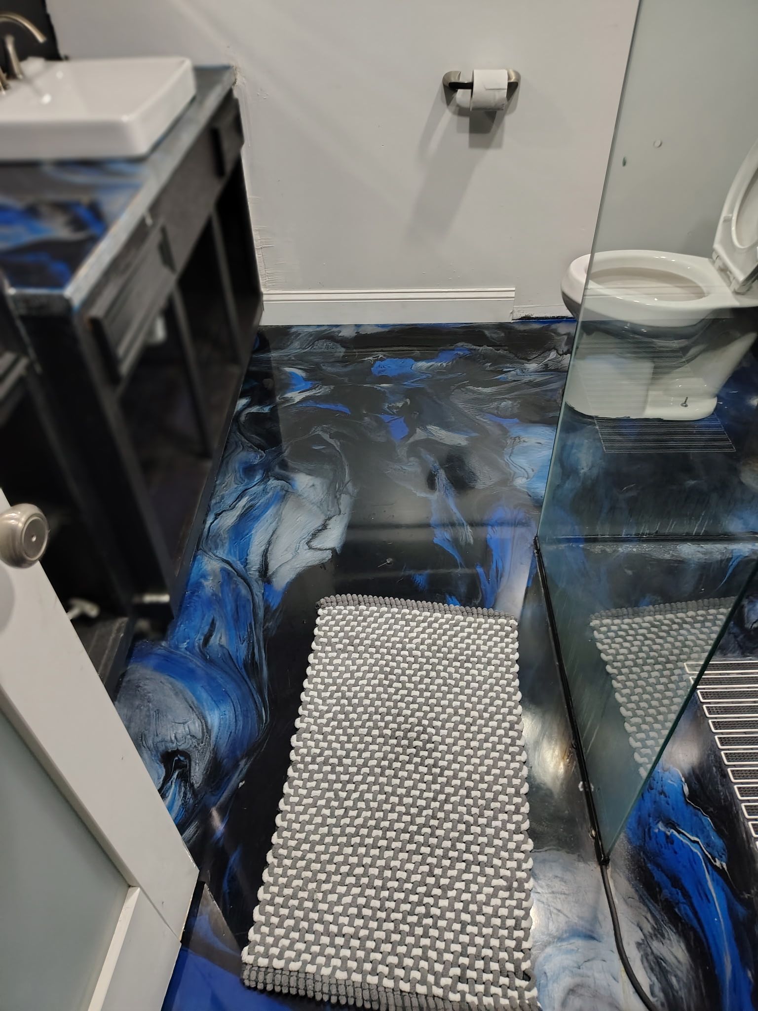 Un baño con cabina de ducha de vidrio, un lavamanos blanco y un inodoro.