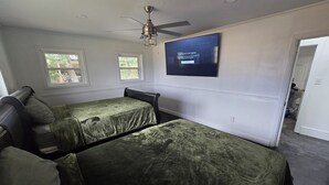 A bedroom with two beds, a ceiling fan, a TV, and windows. - Peaceful 3-bedroom house with AC in charming Jennings (Jennings)