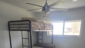 A bunk bed room with a ceiling fan, a window with a view of the outside, and a power outlet on the wall. - Peaceful 3-bedroom house with AC in charming Jennings (Jennings)