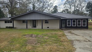 A single-story house with a grey exterior, a front porch, and a driveway. - Peaceful 3-bedroom house with AC in charming Jennings (Jennings)