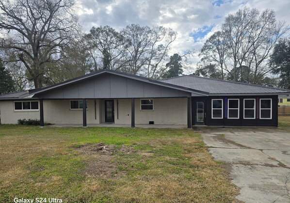 A single-story house with a grey exterior, a front porch, and a driveway.