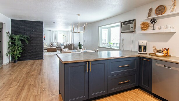 A modern kitchen with dark cabinetry, a central island, and a built-in dishwasher. - 4BR I Gameroom, Queen x4, Kitchens x2, Pac n' play (Fargo)