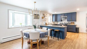 A modern kitchen with a central island, a dining area with a round table, and wooden flooring. - 4BR I Gameroom, Queen x4, Kitchens x2, Pac n' play (Fargo)