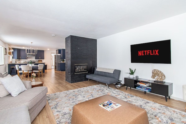 A modern living room with a fireplace, a sofa, a coffee table, and a flat-screen TV mounted on the wall.