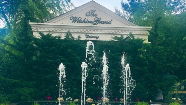 Das Wishime Grand Hotel mit Garten, Brunnen und bunten Blumen.