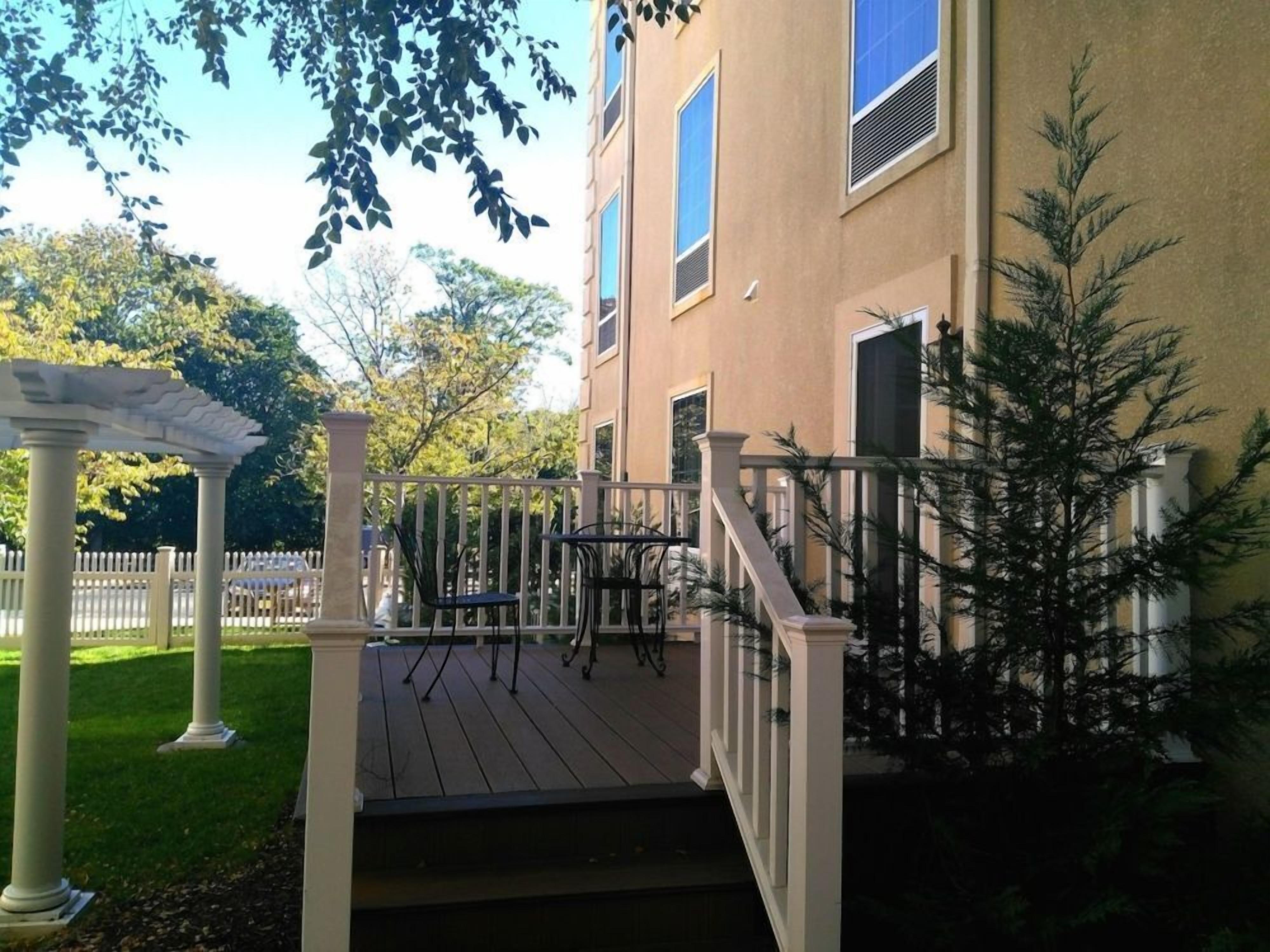 Une terrasse en bois agrémentée d’une pergola et d’un escalier menant à un bâtiment.