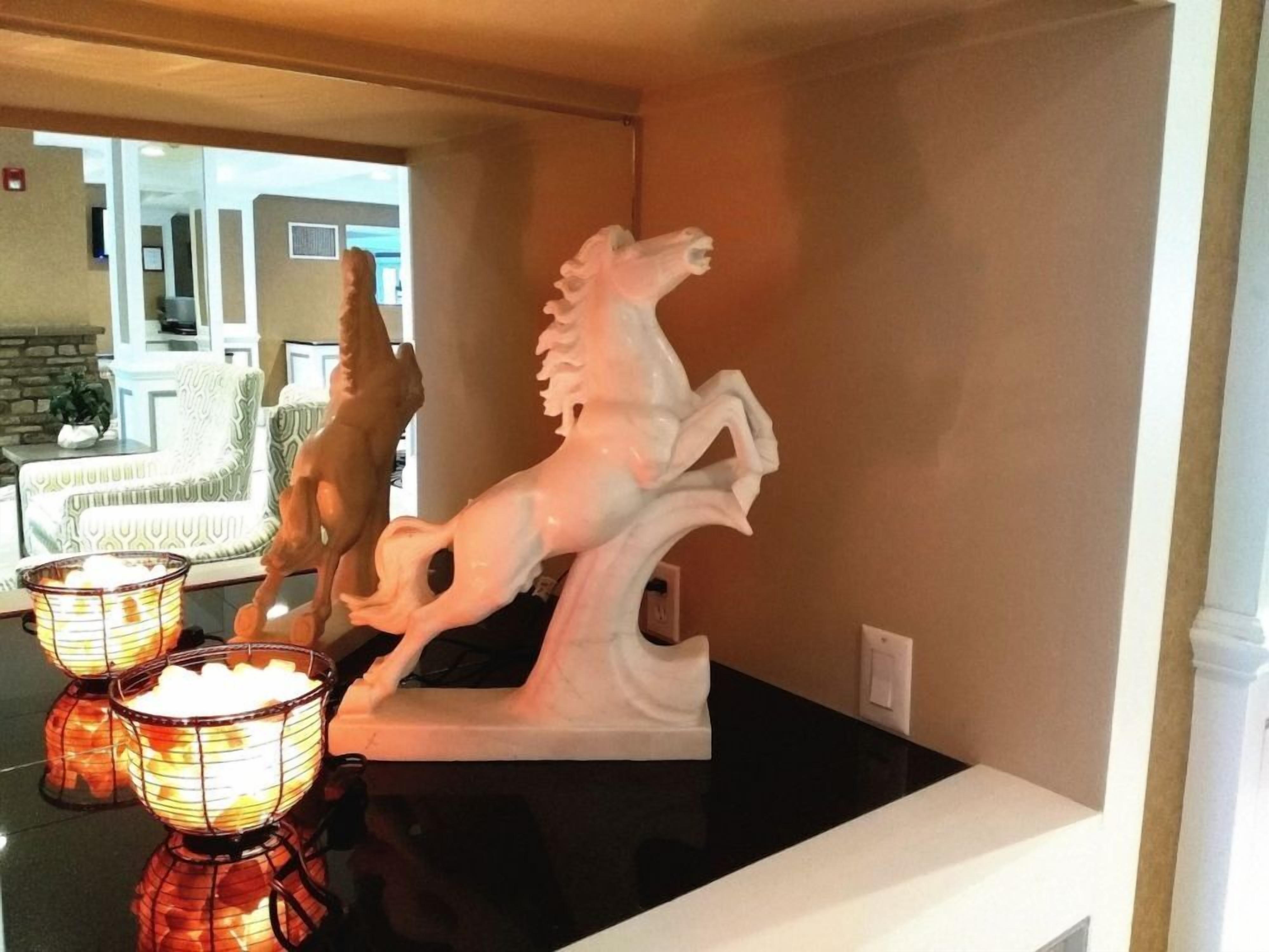 Una habitación con una encimera negra, dos esculturas blancas de caballos y dos candelabros iluminados.
