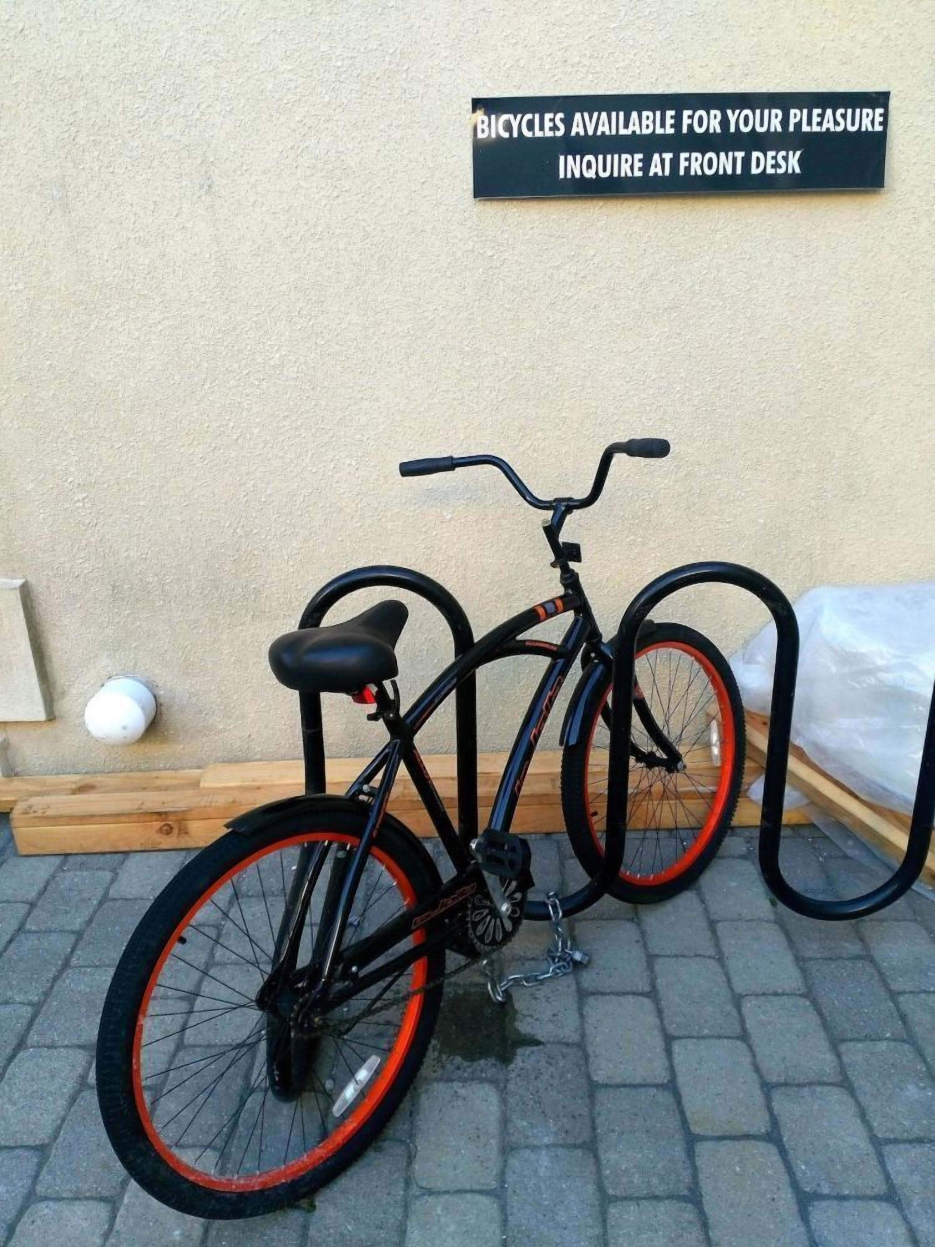 Un vélo est garé contre un mur, et une pancarte indique que des vélos sont disponibles à la location.
