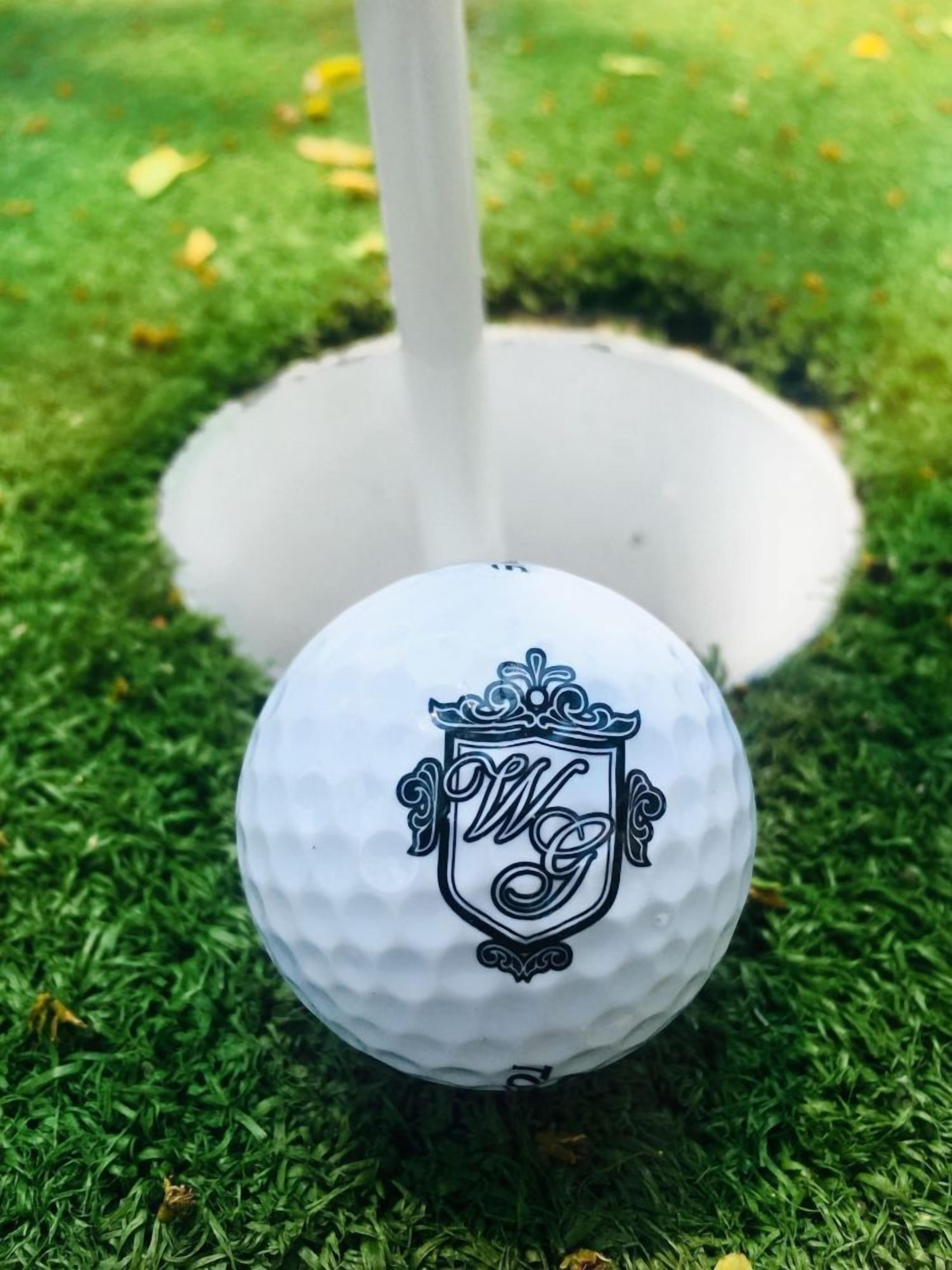 Ein Golfball mit Wappenlogo auf einer grünen Fläche.