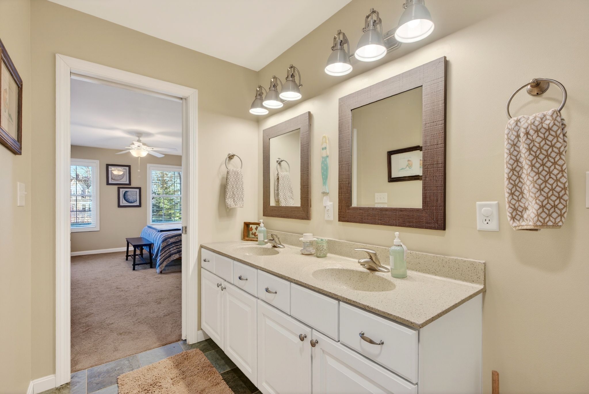 A bathroom with a double sink vanity, a ceiling fan, and a large mirror.