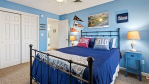 A bedroom with a bed, a ceiling fan, a nightstand, and wall decorations. - 2 min walk to BEACH! 4 Bdrm/outdoor shower (Kennebunkport)