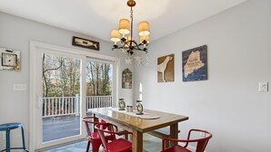 A dining area with a wooden table, red chairs, a chandelier, and artwork on the walls. - 2 min walk to BEACH! 4 Bdrm/outdoor shower (Kennebunkport)