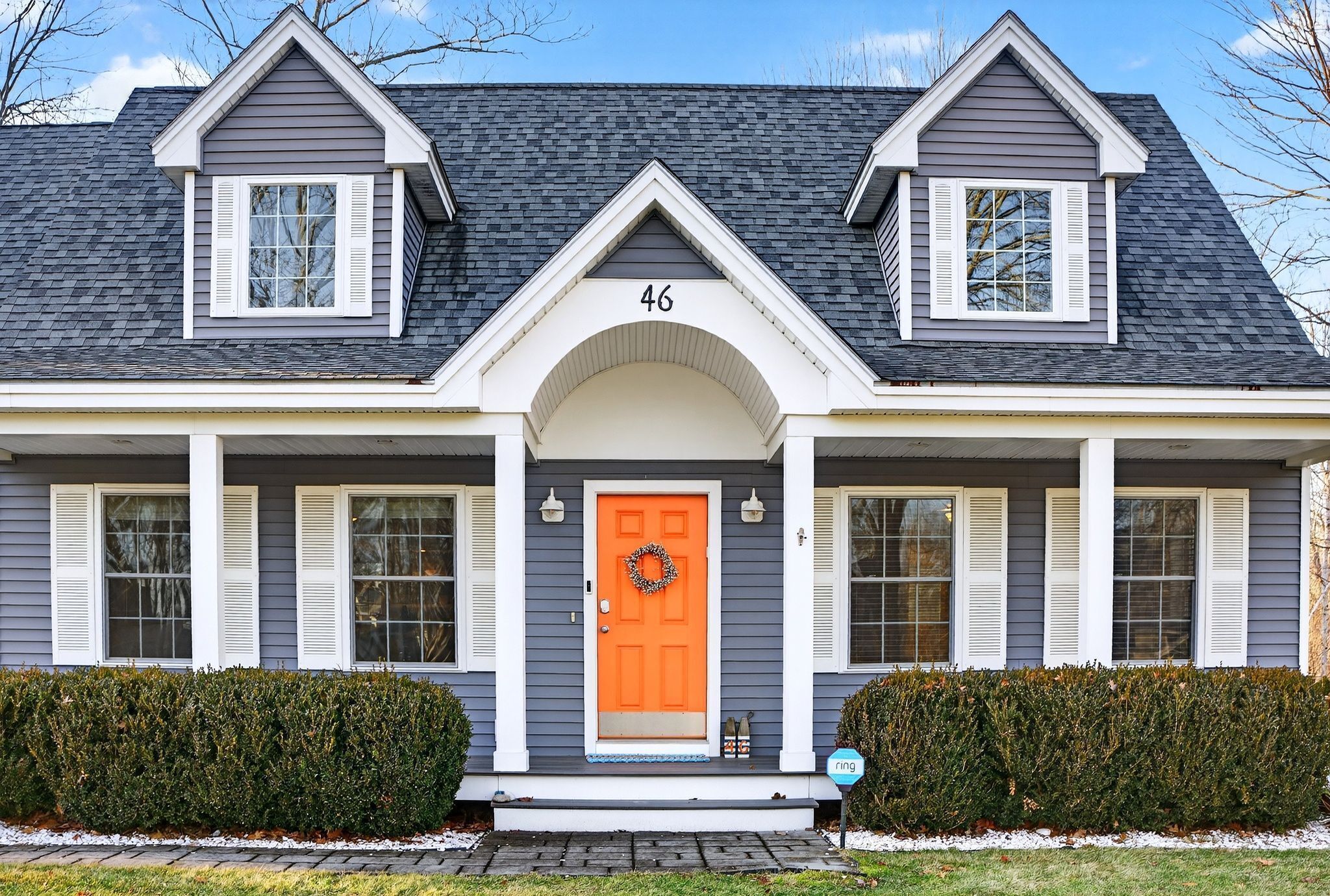 A two-story house with a gray exterior, white trim, and a bright orange front door.
