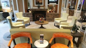 Un hall de hotel con chimenea, sillones estampados, un sofá y una televisión.
