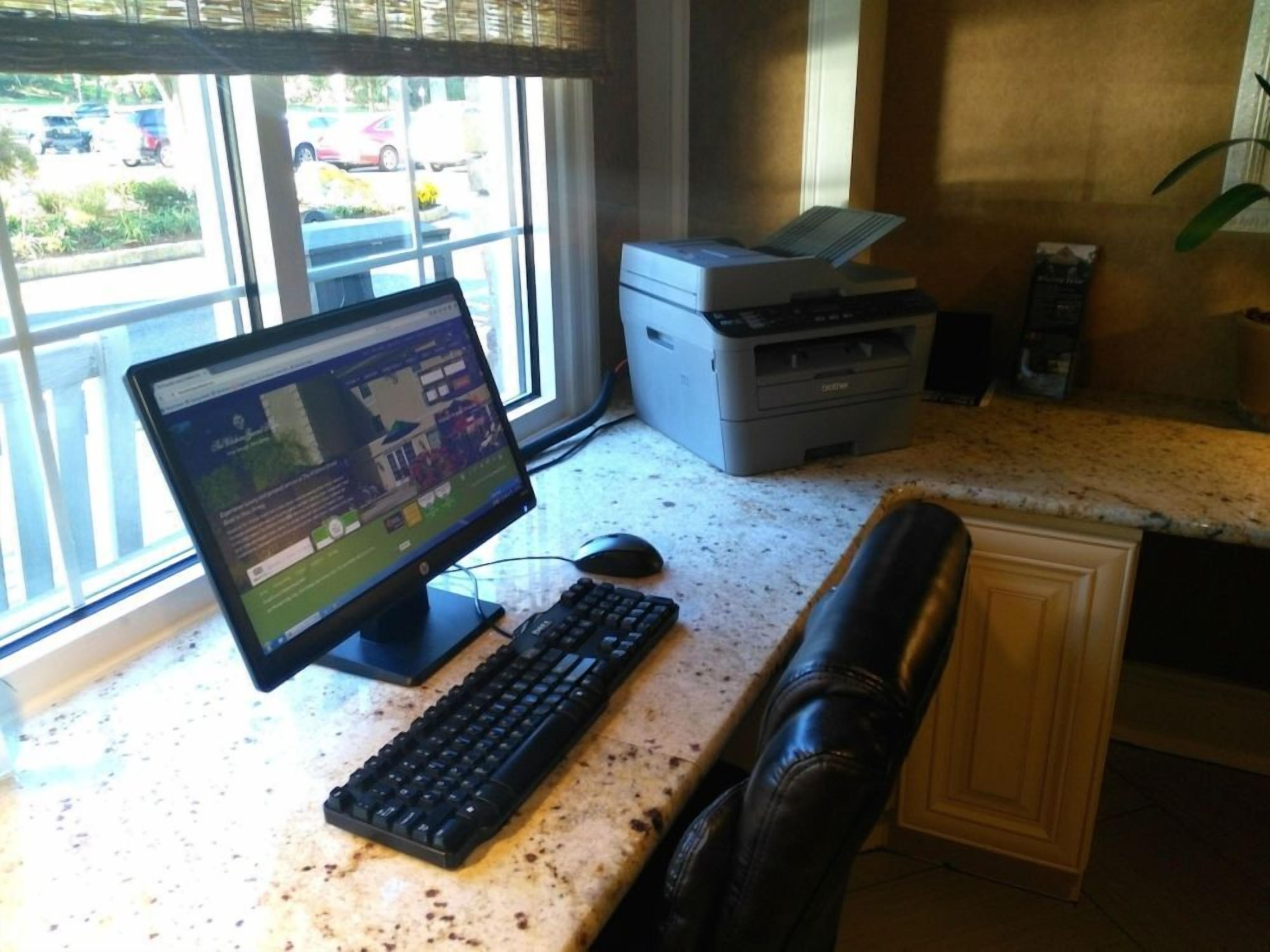 A computer desk with a monitor, keyboard, and mouse.