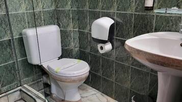 A bathroom with a toilet, sink, and marble tiles.
